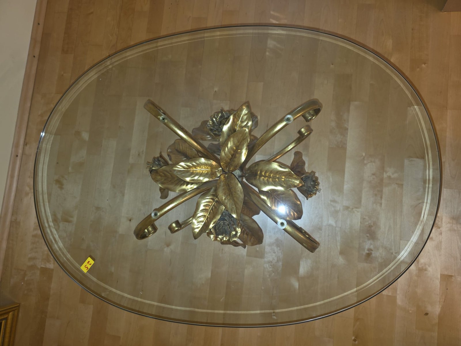 Ovale Glasplatte mit vergoldetem, floralem Untergestell: Ansicht von oben mit Blättern und Blüten.