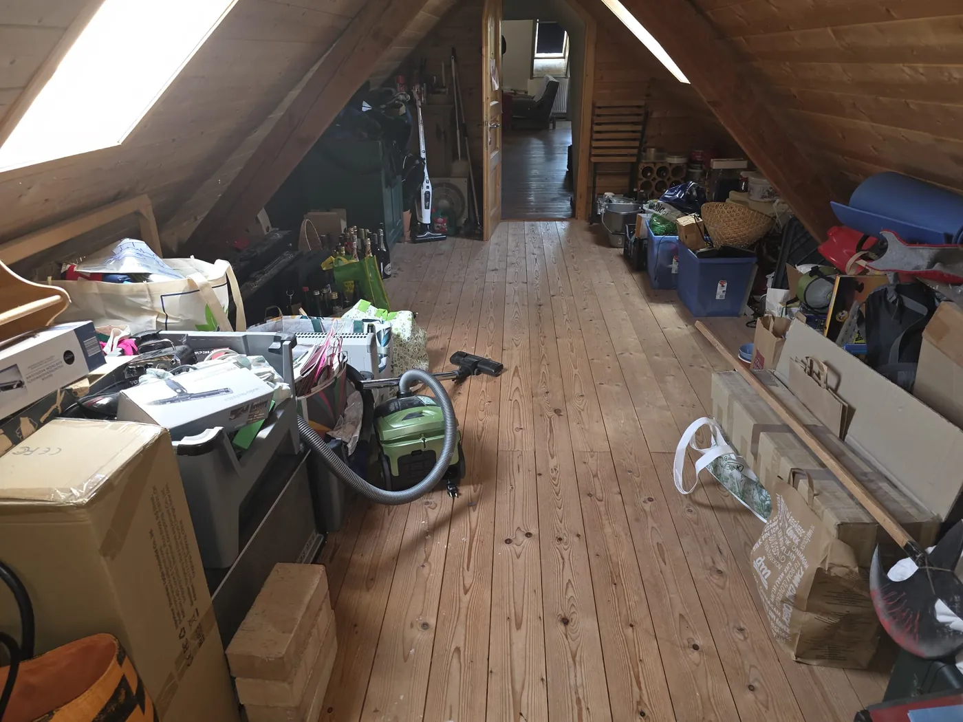 Dachbodenräumung Mistelbach: Dachboden vor der Räumung mit Kartons, Kisten, Taschen, Staubsauger und Hausrat entlang der Dachschrägen