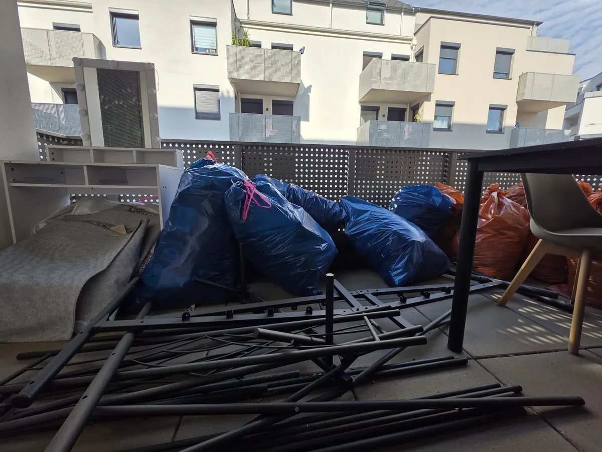 Notfall-Entrümpelung St. Pölten: Balkon mit blauen und orangen Säcken, zerlegtem Metallbettgestell und Möbeln vor der Räumung